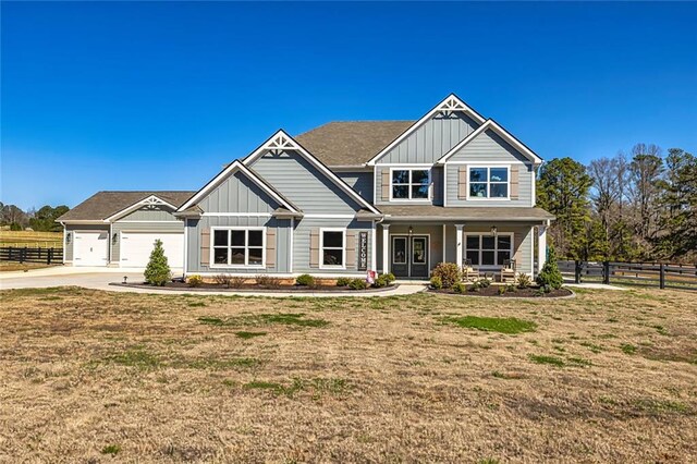 craftsman-style house featuring driveway, fence, a front lawn, and board and batten siding