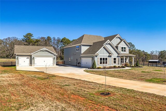 craftsman-style house with board and batten siding, a front lawn, fence, and a garage