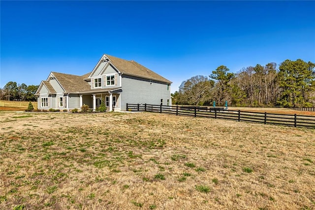 view of side of property featuring a rural view and fence