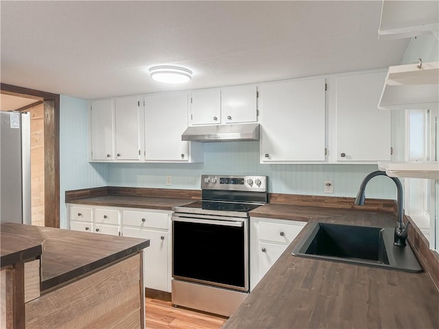 kitchen with stainless steel appliances, under cabinet range hood, dark countertops, a sink, and white cabinetry