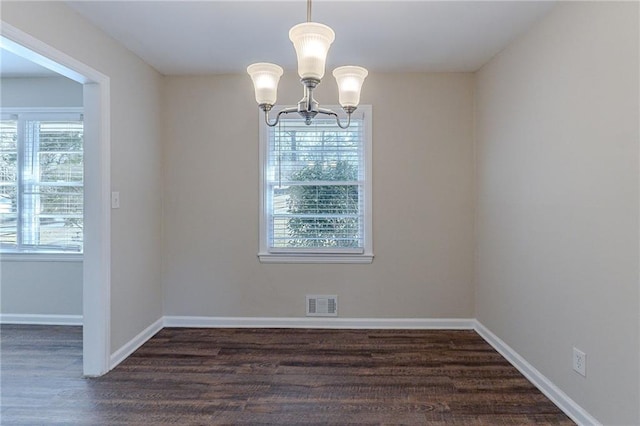 unfurnished dining area with plenty of natural light, a notable chandelier, and dark hardwood / wood-style floors