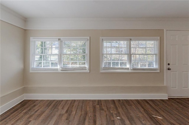 empty room with a healthy amount of sunlight, crown molding, and dark hardwood / wood-style floors