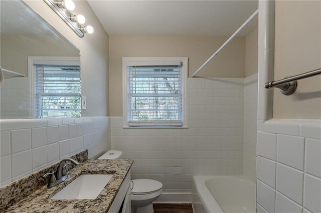 full bathroom featuring toilet, vanity, tile walls, and bathing tub / shower combination