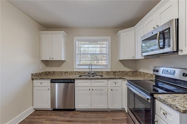 kitchen with sink, white cabinets, light stone counters, and appliances with stainless steel finishes