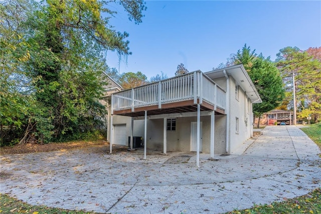 rear view of house with central AC unit, a garage, and a wooden deck