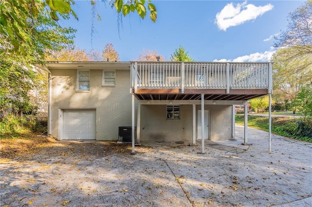 back of property with a garage, central AC unit, and a wooden deck