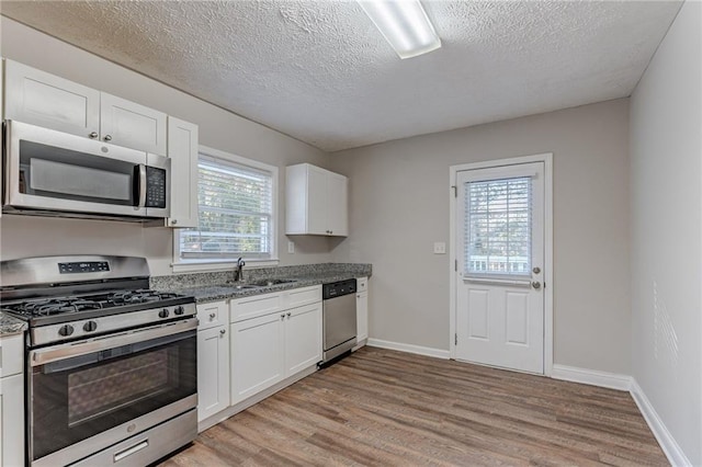 kitchen featuring stainless steel appliances, white cabinetry, and a healthy amount of sunlight