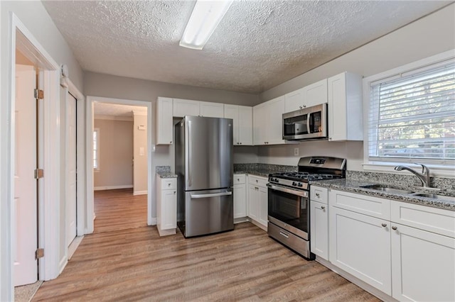 kitchen featuring light wood-type flooring, stainless steel appliances, white cabinetry, and sink