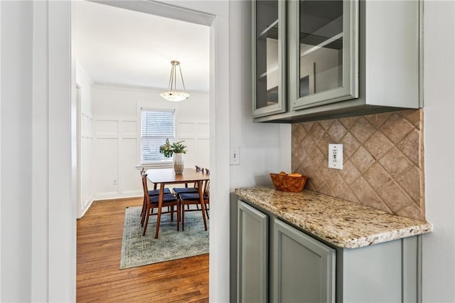 kitchen with light stone counters, tasteful backsplash, crown molding, hanging light fixtures, and dark hardwood / wood-style floors