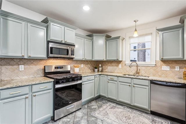 kitchen featuring hanging light fixtures, tasteful backsplash, appliances with stainless steel finishes, and sink