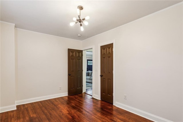 spare room with an inviting chandelier, crown molding, and dark hardwood / wood-style flooring