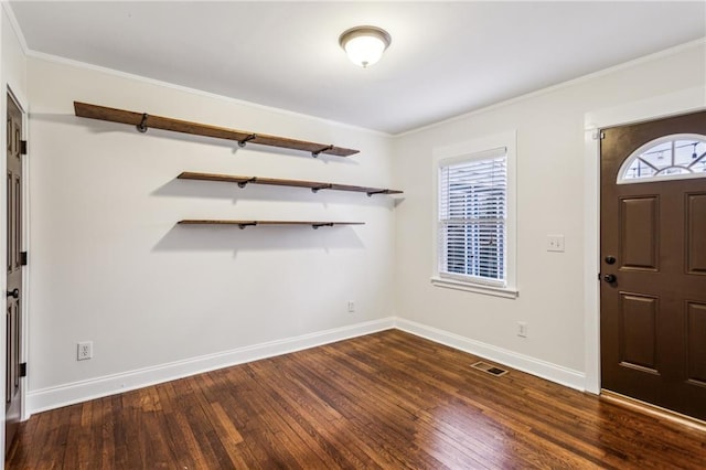 foyer entrance with ornamental molding and dark wood-type flooring