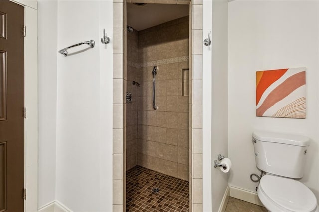 bathroom featuring tile patterned flooring, toilet, and tiled shower