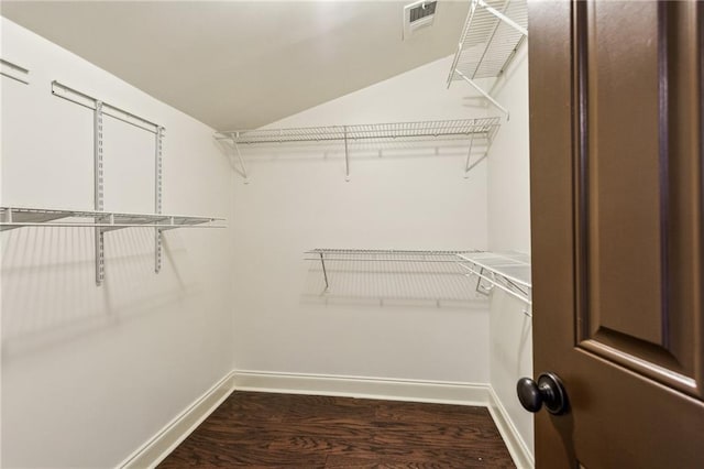 spacious closet with vaulted ceiling and dark hardwood / wood-style floors