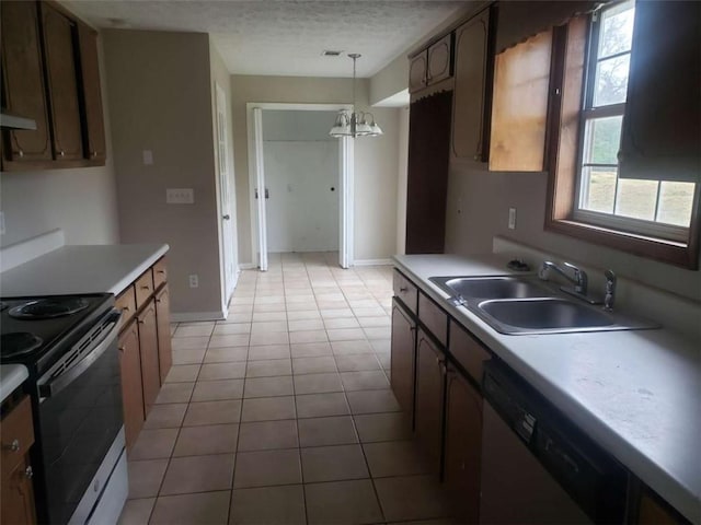 kitchen with light tile patterned floors, a textured ceiling, a sink, hanging light fixtures, and appliances with stainless steel finishes