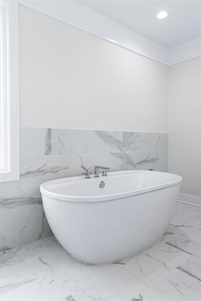 bathroom featuring a tub to relax in and tile walls