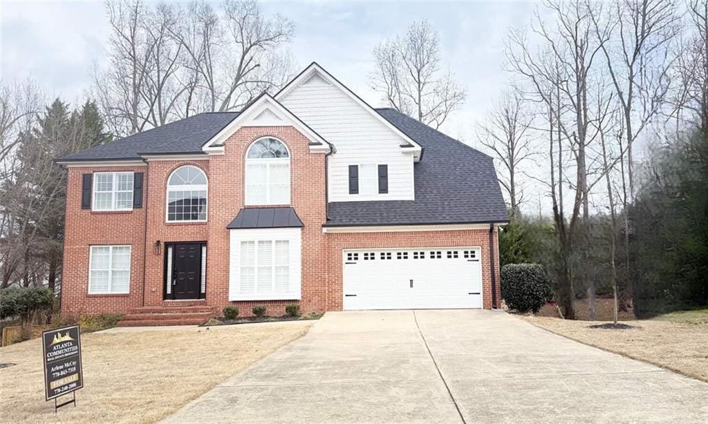 view of front of home featuring concrete driveway, brick siding, and roof with shingles