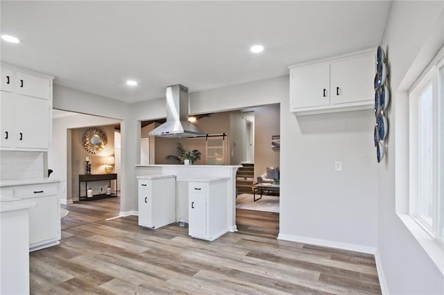 783 Lost Creek Cir, Stone Mountain, GA 30088 - kitchen with island range hood, baseboards, white cabinets, light wood finished floors, and light countertops