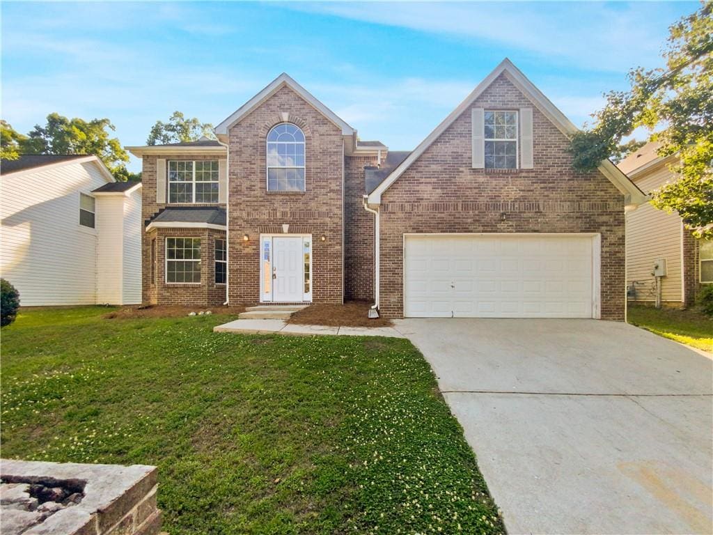 view of property featuring a garage and a front lawn