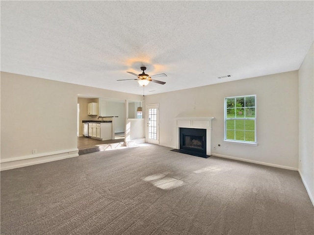 unfurnished living room with ceiling fan, a textured ceiling, and carpet flooring