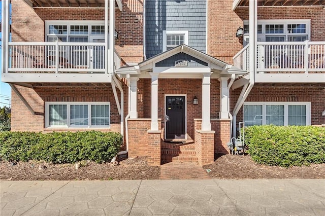 doorway to property featuring brick siding and a balcony