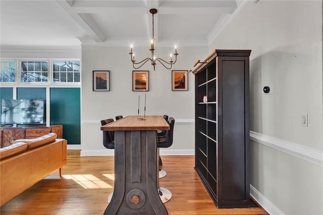 dining space with baseboards, ornamental molding, beam ceiling, and light wood-style floors
