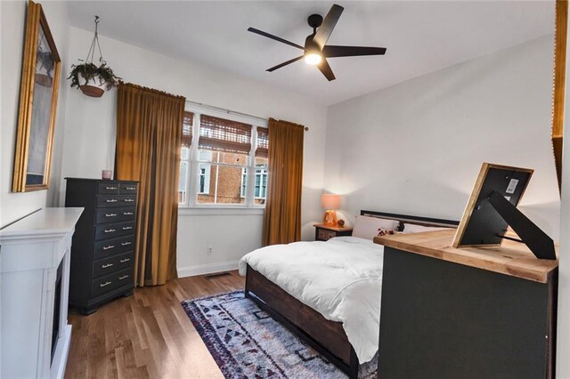 bedroom featuring visible vents, baseboards, ceiling fan, and wood finished floors