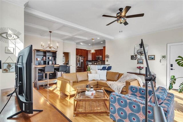 living area featuring coffered ceiling, ornamental molding, light wood-style floors, beam ceiling, and ceiling fan with notable chandelier