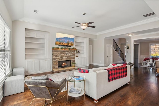 living area with visible vents, built in features, wood finished floors, stairs, and a fireplace