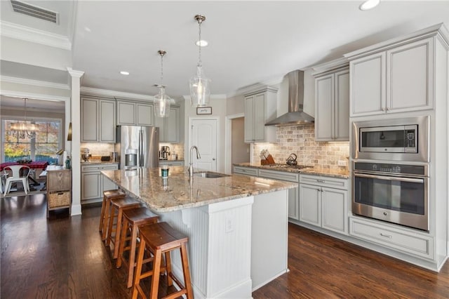 kitchen with stainless steel appliances, gray cabinetry, a sink, and wall chimney exhaust hood