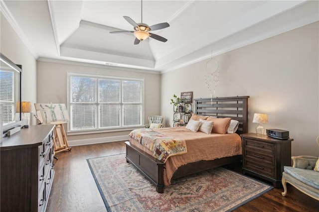 bedroom with a ceiling fan, a tray ceiling, crown molding, and dark wood finished floors