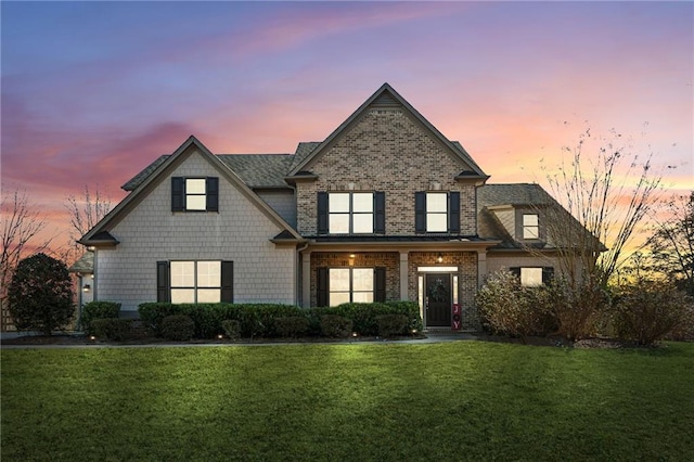 view of front facade with brick siding and a lawn