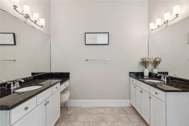 bathroom with tile patterned flooring, two vanities, a sink, and baseboards