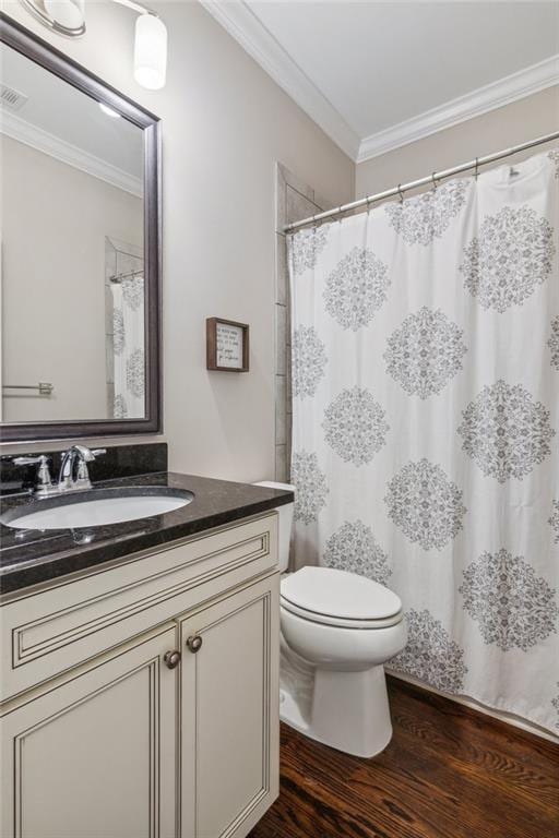 bathroom featuring visible vents, toilet, ornamental molding, wood finished floors, and vanity