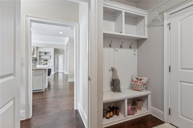 mudroom featuring dark wood-type flooring, built in shelves, and baseboards