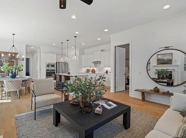 living area with light wood finished floors, ornamental molding, and recessed lighting