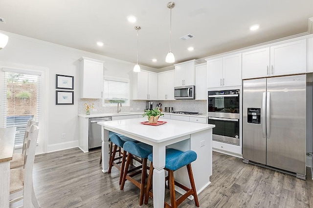 895 Garnet Dr, Acworth, GA 30101 - kitchen with appliances with stainless steel finishes, a kitchen breakfast bar, light countertops, tasteful backsplash, and wood finished floors