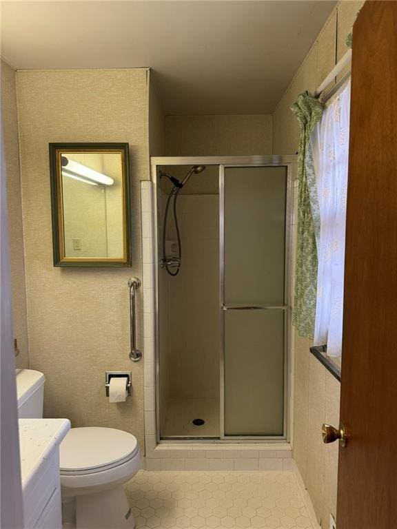 bathroom featuring a shower with door, vanity, and toilet