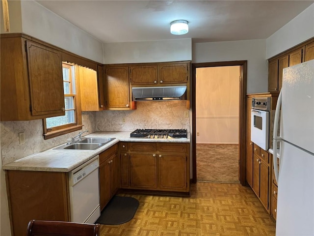 kitchen featuring tasteful backsplash, white appliances, light parquet flooring, and sink