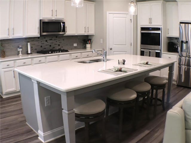 kitchen with a sink, a kitchen breakfast bar, stainless steel appliances, and dark wood finished floors