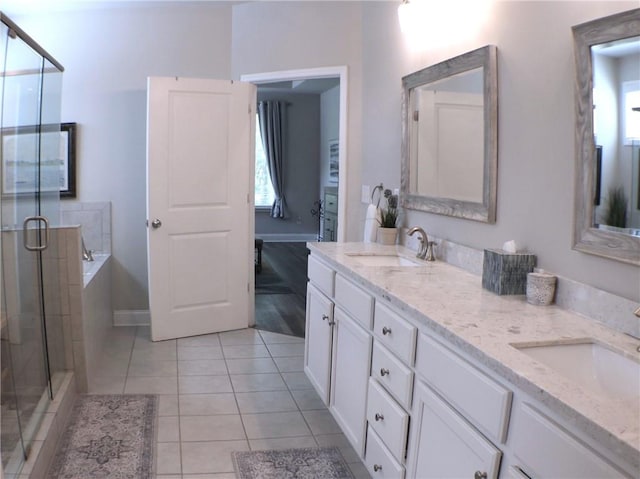 bathroom featuring a garden tub, double vanity, tile patterned floors, a shower stall, and a sink