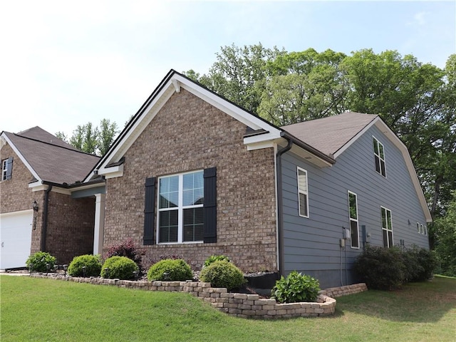view of side of home with a lawn, brick siding, and a garage