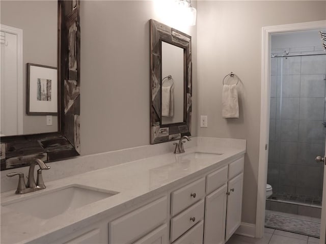 bathroom with double vanity, a sink, toilet, and tiled shower