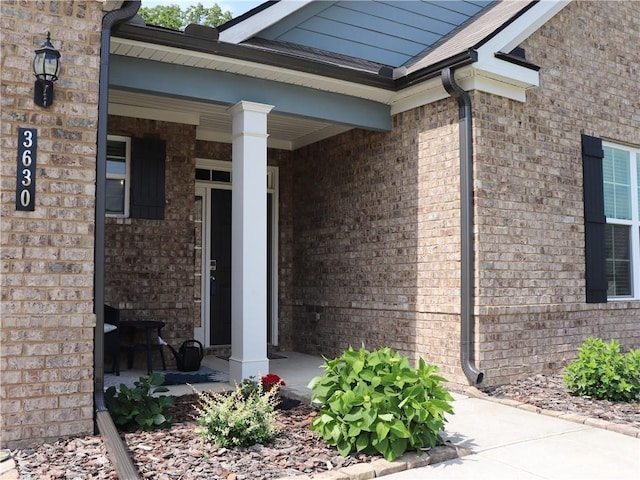 doorway to property with a porch and brick siding