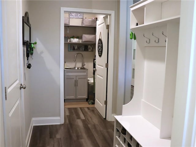 mudroom featuring baseboards, a sink, and dark wood-style floors