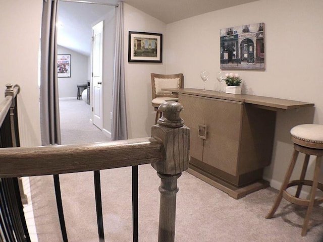interior space featuring light colored carpet, baseboards, and vaulted ceiling