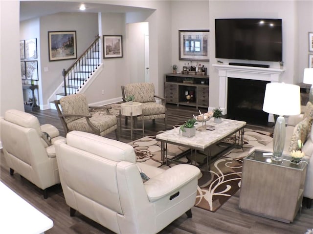 living room with stairs, baseboards, wood finished floors, and a fireplace