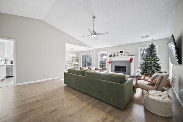 living room with lofted ceiling, ceiling fan with notable chandelier, hardwood / wood-style floors, and a textured ceiling