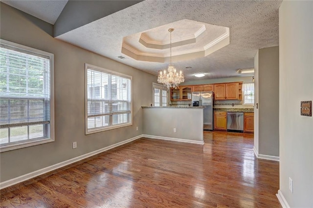 interior space with dark wood-style flooring, a textured ceiling, baseboards, an inviting chandelier, and a tray ceiling