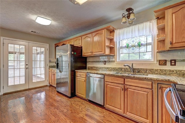 kitchen with open shelves, a sink, stainless steel appliances, light wood-type flooring, and visible vents